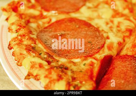 Salami-Pizza auf einem in Stücke geschnittenen Teller. Stockfoto