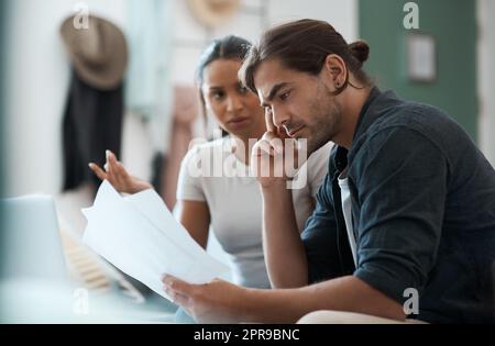 Wie werden wir das beheben? Ein junges Paar, das zu Hause einen Streit hat, während es Papierkram macht. Stockfoto