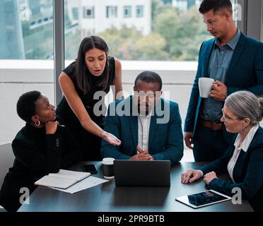 Ich glaube, ich sehe einen Fehler dort: Ein Team von Geschäftsleuten hat sich in einem Büro um einen Laptop versammelt. Stockfoto