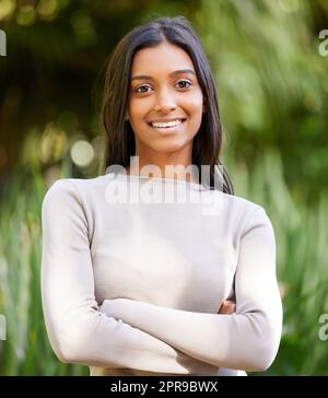 Lächle und die Welt lächelt dich wieder an. Eine schöne junge Frau lächelt, während sie draußen steht. Stockfoto