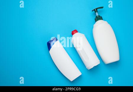 Weiße Plastikflaschen mit Shampoo-Pumpe, Duschgel auf blauem Hintergrund Stockfoto