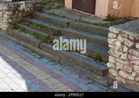 Alte, mit Gras bedeckte Betontreppen, gepflasterter Fußweg Stockfoto