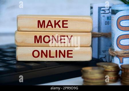 Verdienen Sie online Geld auf Holzblöcken auf dem Computer mit der Tastatur, mit Goldmünzen und Banknoten. Online-Geschäftskonzept. Stockfoto