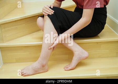 Asiatische Dame Frau Verletzungen durch Herunterfallen auf rutschigen Oberflächen Treppen zu Hause. Stockfoto