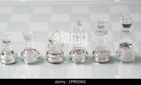 Stücke von transparentem Schach, König, Königin, Ritter (Pferd), Bischof, Rook, Bauer . Transparente Schachfiguren auf Schachbrett. Stockfoto