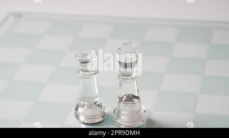 Stücke von transparentem Schach, König und Königin. Transparente Schachfiguren auf Schachbrett. Stockfoto