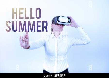 Schild mit der Aufschrift „Hello Summer“. Internetkonzept für die wärmste Jahreszeit kommt nach dem Frühling, nachdem eine Frau eine VR-Brille trägt und mit einem Finger auf wichtige Nachrichten zeigt. Stockfoto