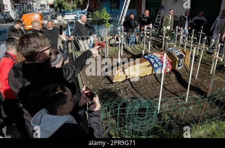 Neapel, Italien. 26. April 2023. Die Fans stehen neben einem Scheingrab für einen Sarg, der mit den Schals der Fußballmannschaften FC Inter FC Juventus und AC Mailand geschmückt ist und mit den Symbolen aller italienischen Fußballmannschaften der Serie A vor einem SSC Napoli-Fanclub kreuzt. Während Neapel schon nächsten Sonntag die Fußballmeisterschaft der Serie A gewinnen könnte, sind die Vorbereitungen für die Feierlichkeiten in der Stadt in vollem Gange. Kredit: Unabhängige Fotoagentur/Alamy Live News Stockfoto