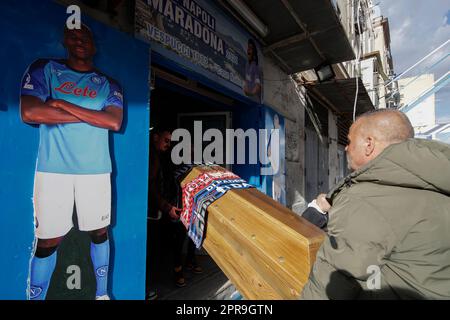 Neapel, Italien. 26. April 2023. Die Fans veranstalten eine Scheinbeerdigung mit einem Sarg, der mit den Schals der Fußballmannschaften FC Inter, FC Juventus und AC Mailand geschmückt ist, vor einem SSC Napoli Fanclub, vorbei an einem Ausschnitt von Neapels Stürmer Victor Osimhen. Während Neapel schon nächsten Sonntag die Fußballmeisterschaft der Serie A gewinnen könnte, sind die Vorbereitungen für die Feierlichkeiten in der Stadt in vollem Gange. Kredit: Unabhängige Fotoagentur/Alamy Live News Stockfoto