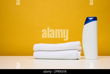 Weiße Plastikflasche für Gel und Shampoo und gedrehte weiße Frotttücher Stockfoto