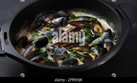 Blaue Miesmuscheln in Sahneweinsauce mit Knoblauch und Kräutern geschmort. Traditionelle italienische oder französische Küche Stockfoto