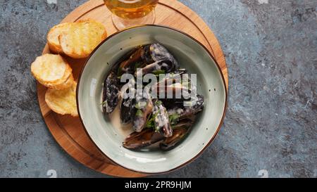 Blaue Miesmuscheln in Sahneweinsauce mit Knoblauch und Kräutern geschmort. Traditionelle italienische oder französische Küche Stockfoto