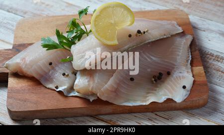 Frisches Tilapia-Fischfilet in Scheiben für Steak oder Salat mit Kräutern, Gewürzen und Zitrone Stockfoto