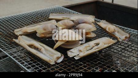 Frische, kurzhalsige Muschel und Razor Clam auf dem Grillnetz Stockfoto