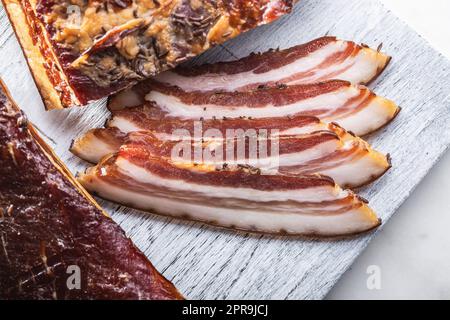Scheiben geräucherter Speck auf Schneidebrett. Stockfoto