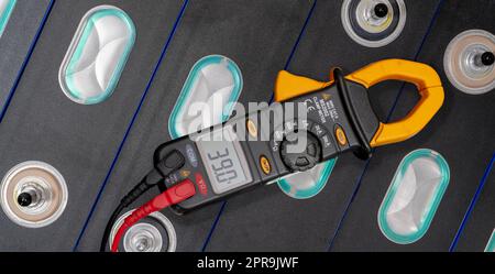 Lithium-NMC-Batterie für Elektrofahrzeuge. Batterie für Elektroautos. Lithium-Ionen-Akkupack. Lithium-NMC-Akku. Energiespeicher für Elektrofahrzeuge. Voltmeter misst die Spannung der Batterie des Elektrofahrzeugs. Stockfoto