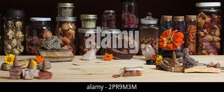 Meditationsaltar mit Steinkristallen und Blumen. Kräutergläser im Hintergrund Stockfoto