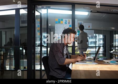 Er widmete sich seiner Arbeit. Ein Geschäftsmann, der in seinem Büro arbeitet. Stockfoto