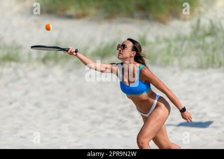 Frau spielt Strandtennis an einem Strand. Professionelles Sportkonzept. Horizontales Sport-Thema Poster, Grußkarten, Header, Website und App Stockfoto