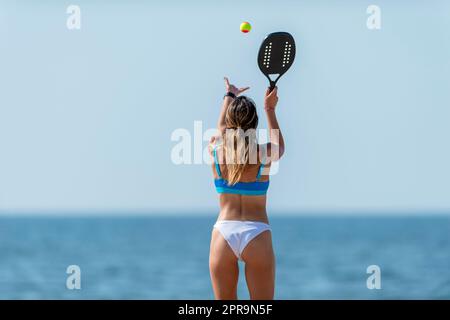 Frau spielt Strandtennis an einem Strand. Professionelles Sportkonzept. Horizontales Sport-Thema Poster, Grußkarten, Header, Website und App Stockfoto