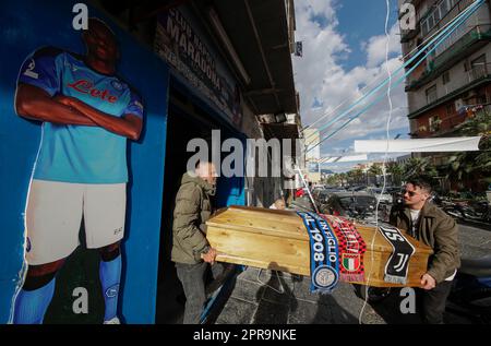 Neapel, Italien. 26. April 2023. Die Fans veranstalten eine Scheinbeerdigung mit einem Sarg, der mit den Schals der Fußballmannschaften FC Inter, FC Juventus und AC Mailand geschmückt ist, vor einem SSC Napoli Fanclub, vorbei an einem Ausschnitt von Neapels Stürmer Victor Osimhen. Während Neapel schon nächsten Sonntag die Fußballmeisterschaft der Serie A gewinnen könnte, sind die Vorbereitungen für die Feierlichkeiten in der Stadt in vollem Gange. Kredit: Unabhängige Fotoagentur/Alamy Live News Stockfoto