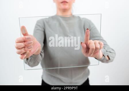 Weibliche Berufstätige, Die Während Der Datenanzeige Auf Transparentes Glas Zeigen. Frau Trägt Ein Elegantes Lässiges Präsentationsbanner Und Fördert Das Geschäft Für Fortschritt. Stockfoto