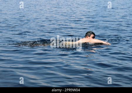 Ein bärtiger Mann schwimmt im Meer. Konzept Sommerurlaub, gesunder Lebensstil Stockfoto