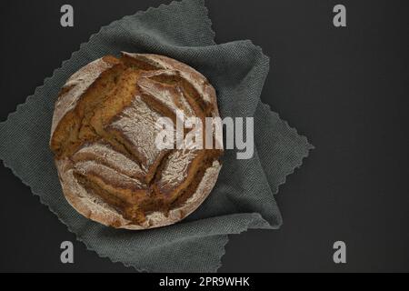 Brotlaib auf einem grauen Küchenhandtuch, schwarze Tafel Stockfoto