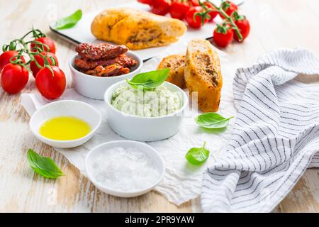 Avocado verteilen und sonnengetrocknete Tomaten mit Olivenöl als Antipasto und Baguette Stockfoto