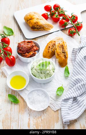 Avocado verteilen und sonnengetrocknete Tomaten mit Olivenöl als Antipasto und Baguette Stockfoto