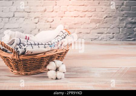 Ein Stapel Bio-Küchenhandtücher in einem Korb mit Baumwollblumen. Konzept der Nachhaltigkeit Stockfoto