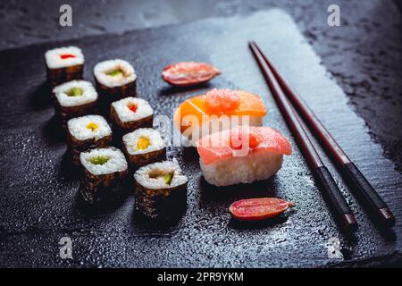 Auswahl an veganem Sushi mit Gemüse, Seitan, Konjakpflanze, Tofu als Fischersatz, mit Fingerkalk als Kaviar auf Schwarz Stockfoto