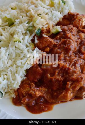 Butterhähnchen mit Basmati-Reis auf einem weißen Teller Stockfoto