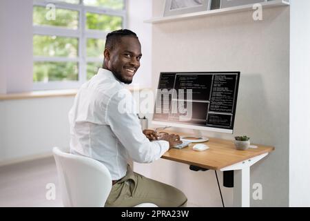 Afroamerikanischer Coder Mit Computer Am Schreibtisch Stockfoto