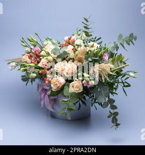 Blumenstrauß in Pastelltönen, bestehend aus Rosen, anderen verschiedenen Blumen und grünen Zweigen. Stockfoto