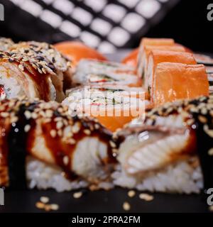 Philadelphia mit Frischkäse, Lachs, Gurke und Kaviar liegt unter saftigem Nigiri-Sushi. Stockfoto