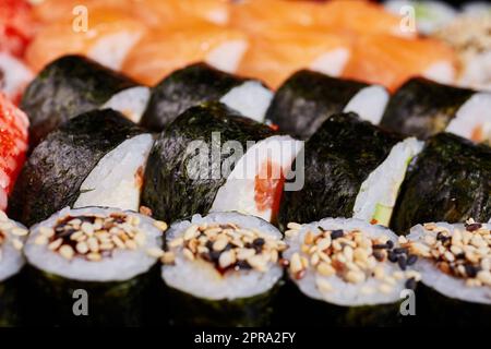 Nahaufnahme der Rolle mit Lachs- und Sesamsamen, in Nori-Blätter eingewickelt. Stockfoto
