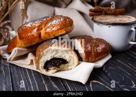 Frisch gebackene duftende hausgemachte Brötchen mit Marmelade auf rustikalem Holztisch. Stockfoto