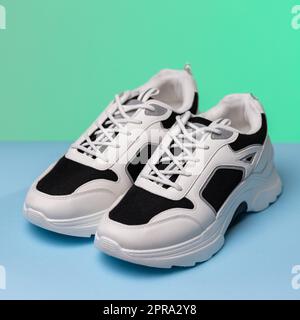 Nahaufnahme der modischen schwarz-weißen Sneaker auf blauem und grünem Hintergrund. Stockfoto