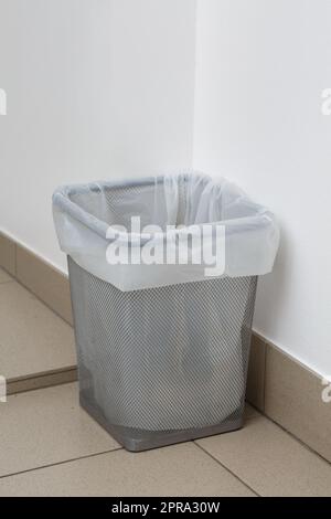 Nahaufnahme eines metallgrauen Mülleimers mit weißem Müllsack im Inneren. Stockfoto