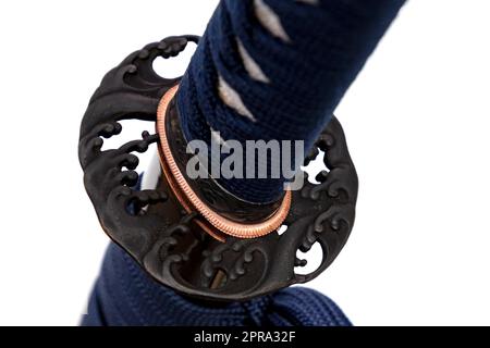 Wave Design Tsuba: Japanischer Schwert-Handschutz aus Stahl. Schwertgriff und Schutzhülle mit marineblauer Schnur, schwarzer Degenschwanz, isoliert auf weißem Hintergrund. Stockfoto