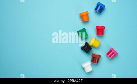 Kunststoffgläser mit mehrfarbigem Gouache auf blauem Hintergrund Stockfoto