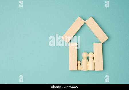 Hölzerne Familienfiguren, Modellhaus auf blauem Hintergrund. Immobilienkauf Stockfoto