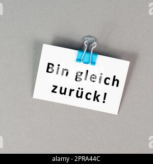 Ich komme bald wieder steht in deutscher Sprache auf einem Papier, macht eine Pause, hinterlässt eine Nachricht auf dem Schreibtisch Stockfoto