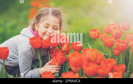 Nettes Mädchen pflücken rote Tulpen im Strauß im Garten. Stockfoto