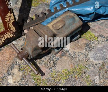 Ein alter Schraubstock steht auf einem gepflasterten Boden. Stockfoto