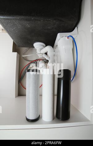 Hauswasserfiltersystem in trinkbaren Zustand, Umkehrosmose. Filterkartuschen aus geschäumtem Polypropylen, Granulat und Briketts Kohlenstoff darunter Stockfoto