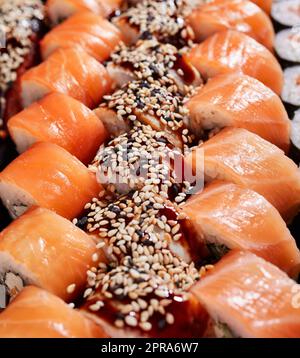 Drei Reihen Sushi-Brötchen mit Lachs und Thunfisch aus nächster Nähe. Stockfoto