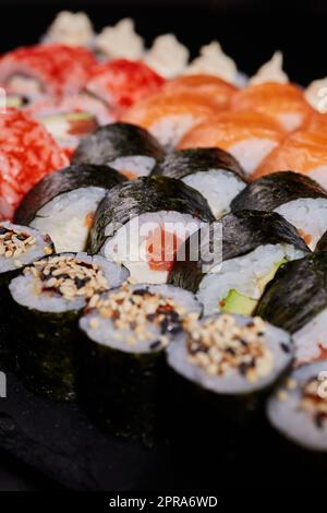 Traditionelle japanische Küche. Bild eines Sushi-Sets mit Maki-Brötchen im Vordergrund. Stockfoto