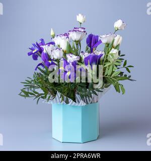 Strauß von eustoma in einer türkisfarbenen Pappschachtel auf blauem Hintergrund. Stockfoto